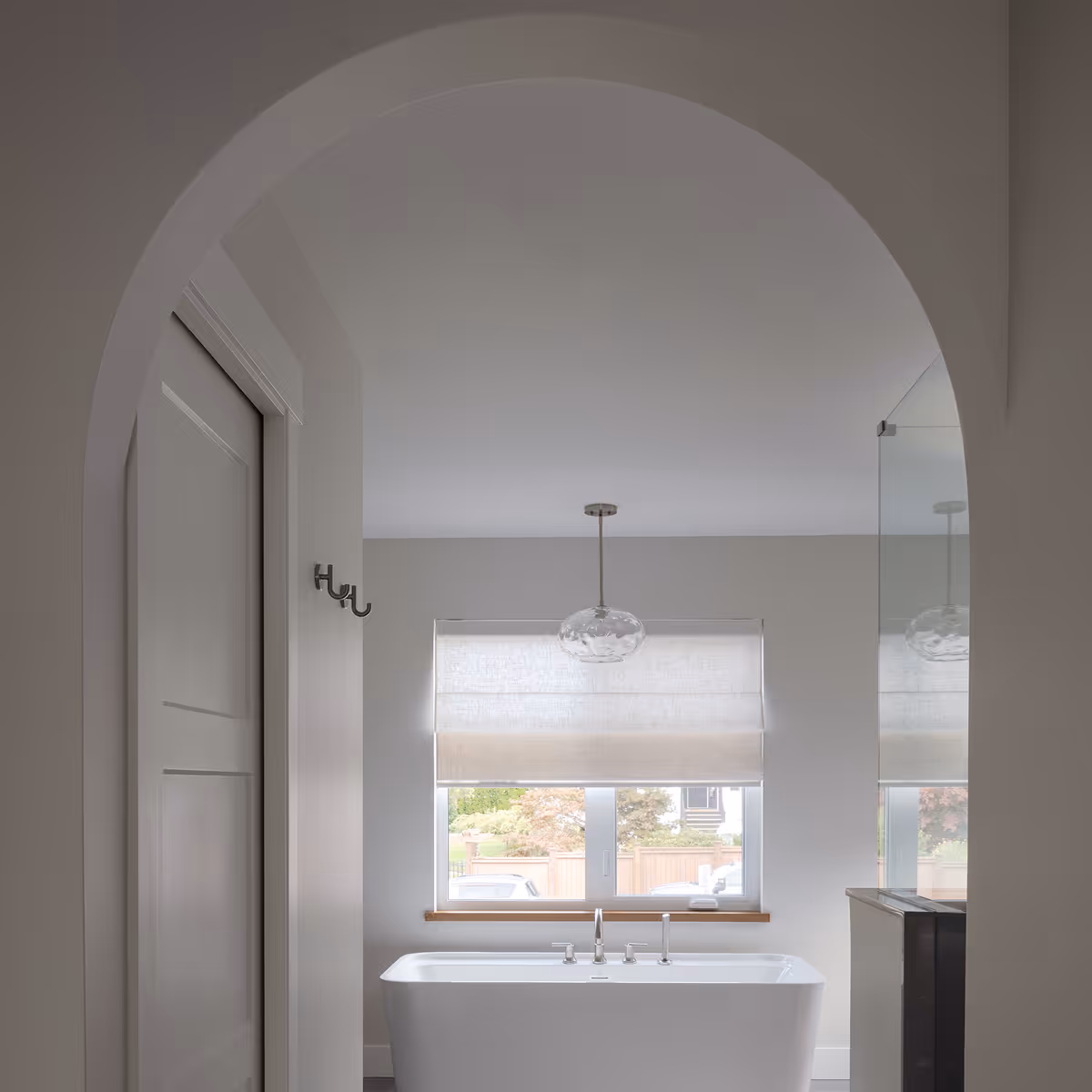 Arched doorway leading into a spa-like bathroom in The Second Act with elegant tile and organic finishes