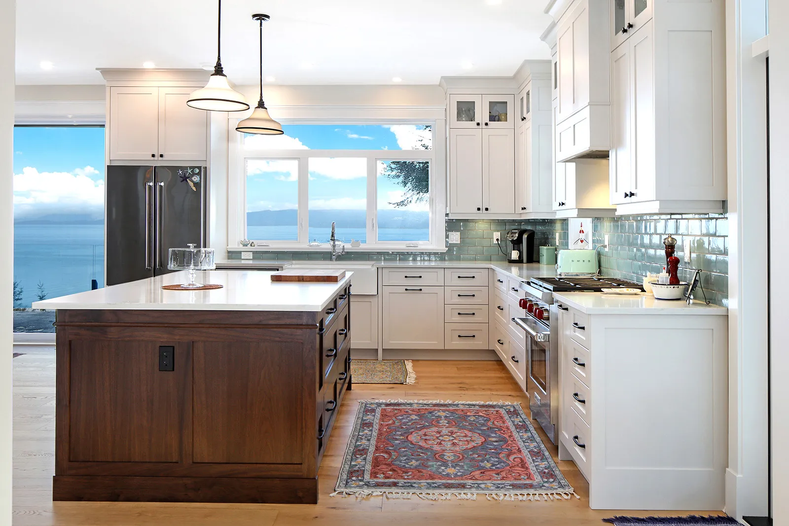 Gourmet kitchen in Seabank Cottage with dark wood island, white cabinetry, and ocean-inspired seagreen tile backsplash