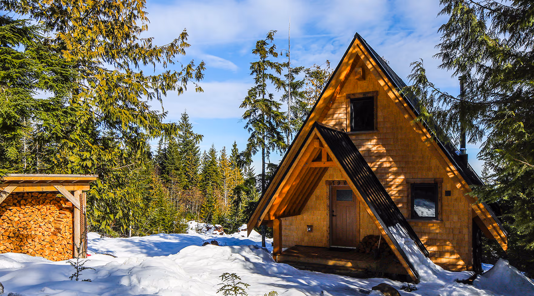 Back exterior view of A Plus custom A-frame cabin showing walk-out design and forest setting at Forbidden Plateau