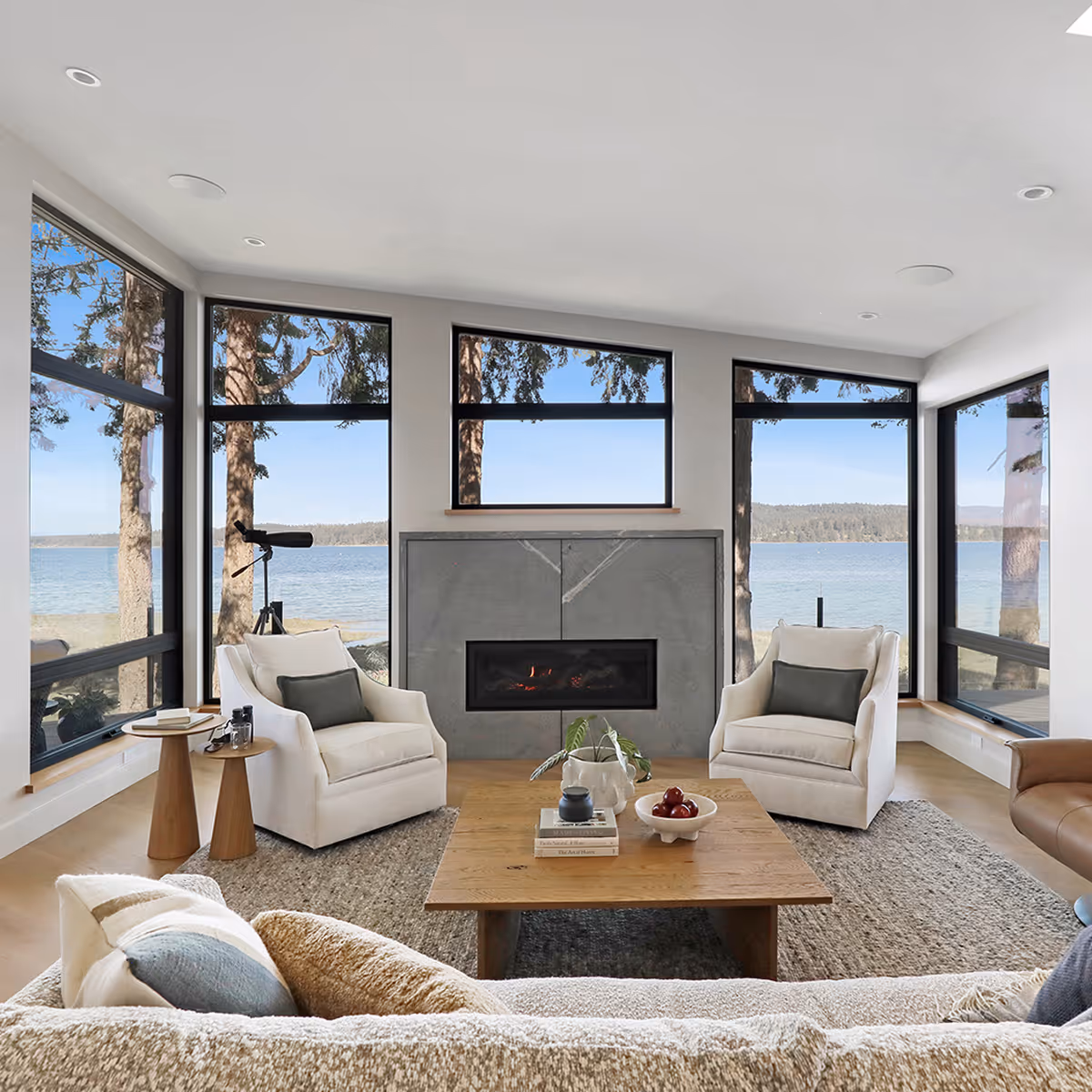 Living room in Coastal Point with large windows framing ocean and forest views, designed for aging in place