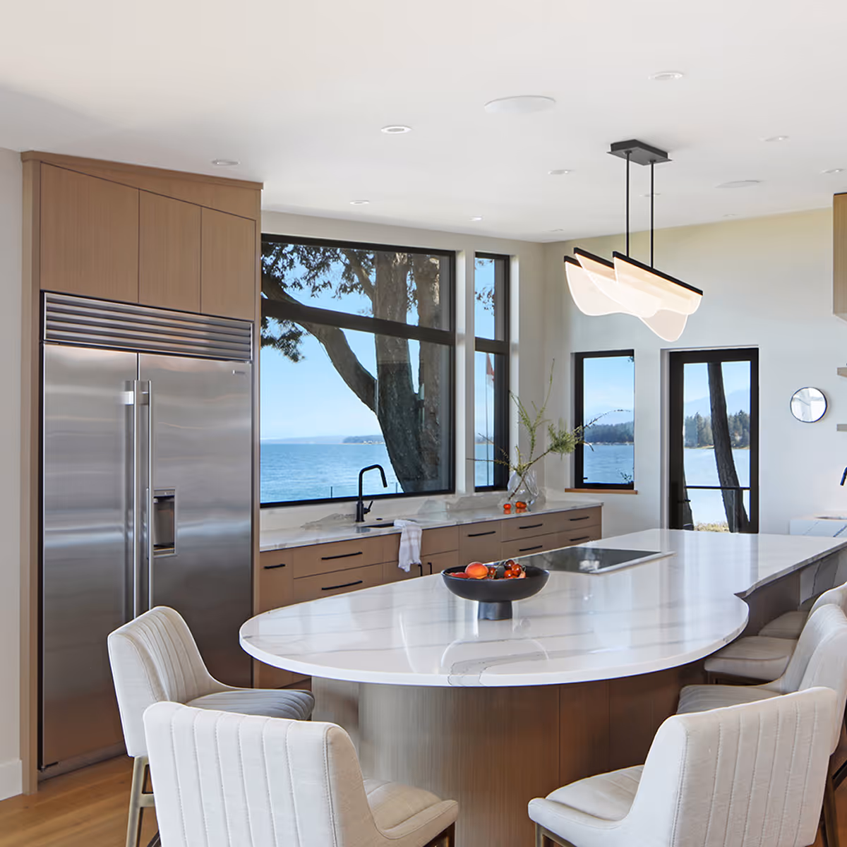 Modern open-concept kitchen of Coastal Point renovation with floor-to-ceiling wine cabinets visible beyond