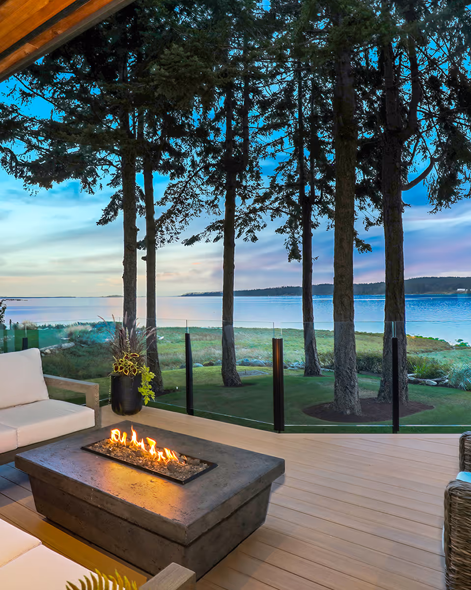 Outdoor patio fireplace overlooking the ocean at a Facet Custom Builders award-winning coastal renovation