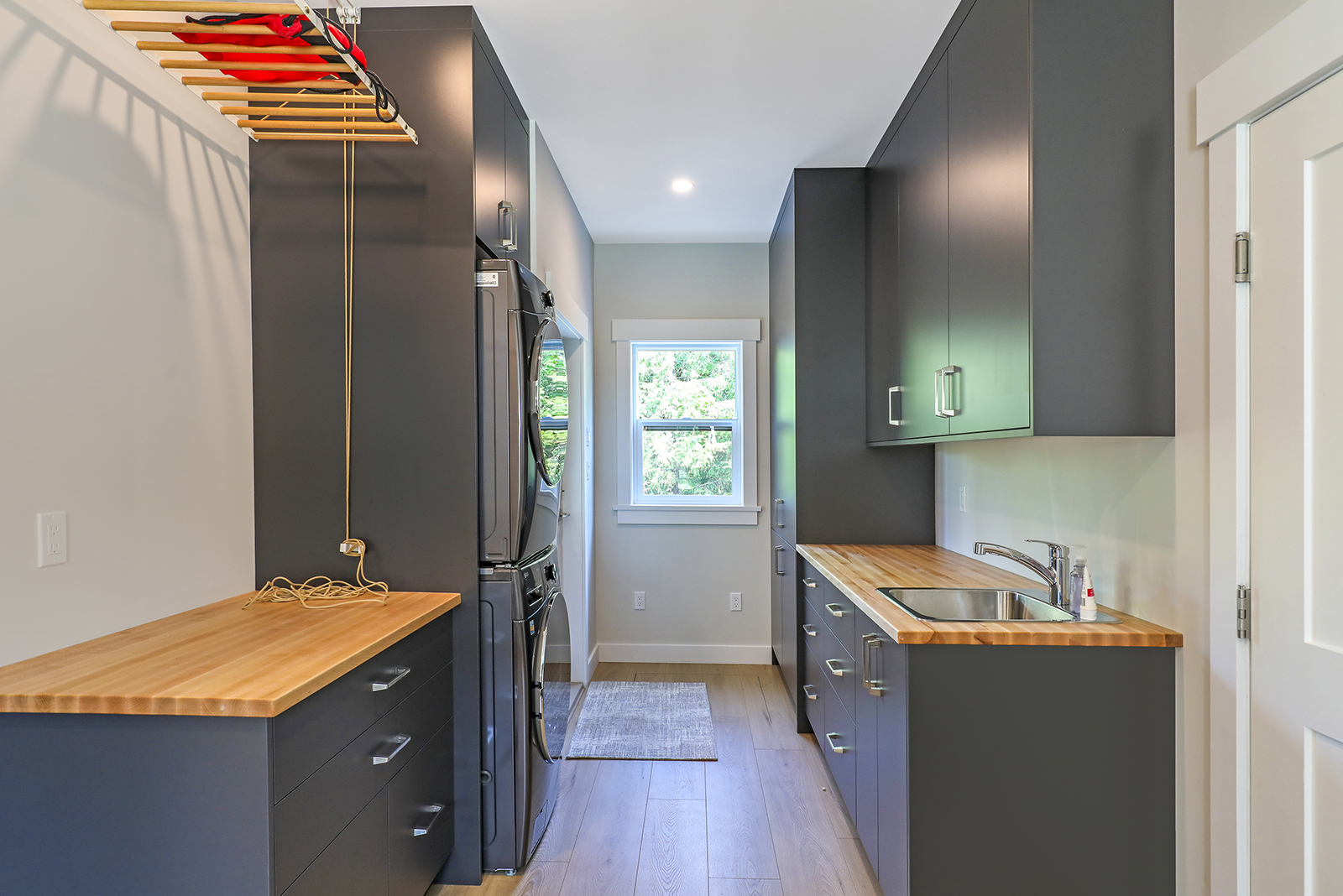 Laundry and entry combination showing grey cupboards and drying rack