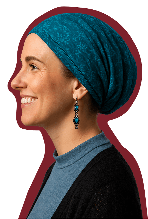 Smiling woman in profile wearing a teal headscarf, dangling earrings, blue top, and black cardigan.