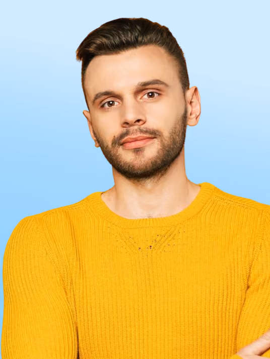 Man with a beard and short hair wearing a yellow sweater against a gradient blue background.