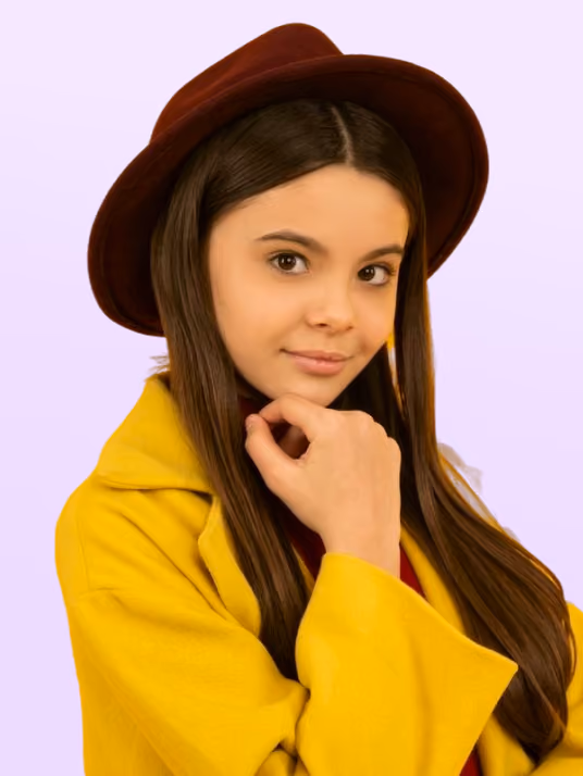 Young woman wearing a brown hat and yellow coat, posing with her hand near her chin against a light purple background.
