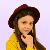 Young woman with long brown hair wearing a maroon hat and yellow coat against a light purple background.