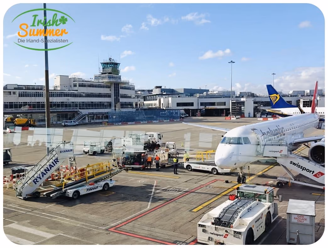 Flugzeug von Ryanair an einem Flughafen-Tor, umgeben von Bodenpersonal und Fahrzeugen zur Gepäckabfertigung.