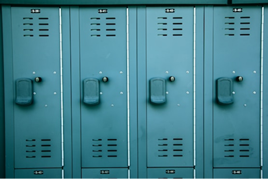 A row of teal metal lockers with vents and built-in handles, aligned side by side against a wall.