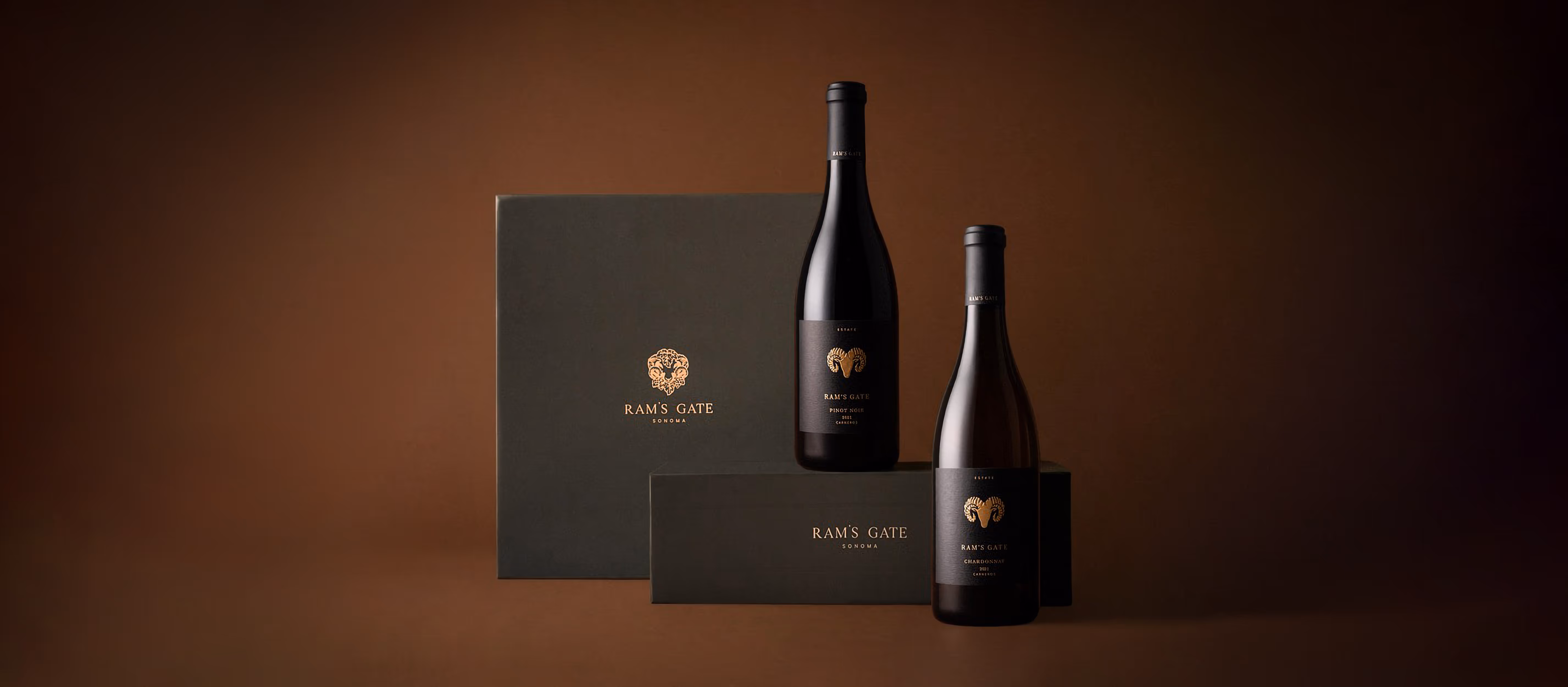 Two premium Ram's Gate wine boxes sitting side by side with two wine bottles in a moody earthy tone background.