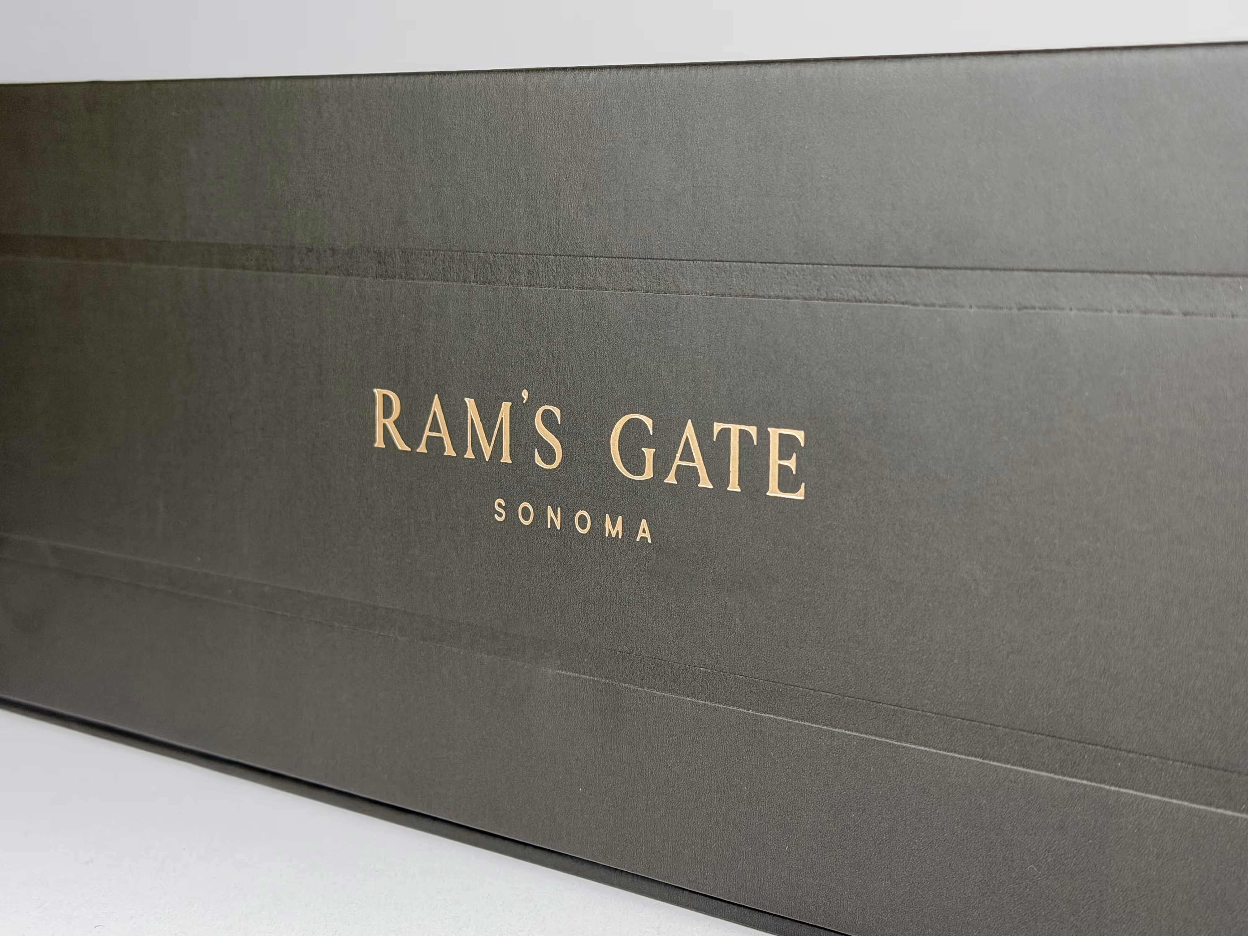 Closeup of the rose gold foil Ram's Gate logotype on the side of the wine box.