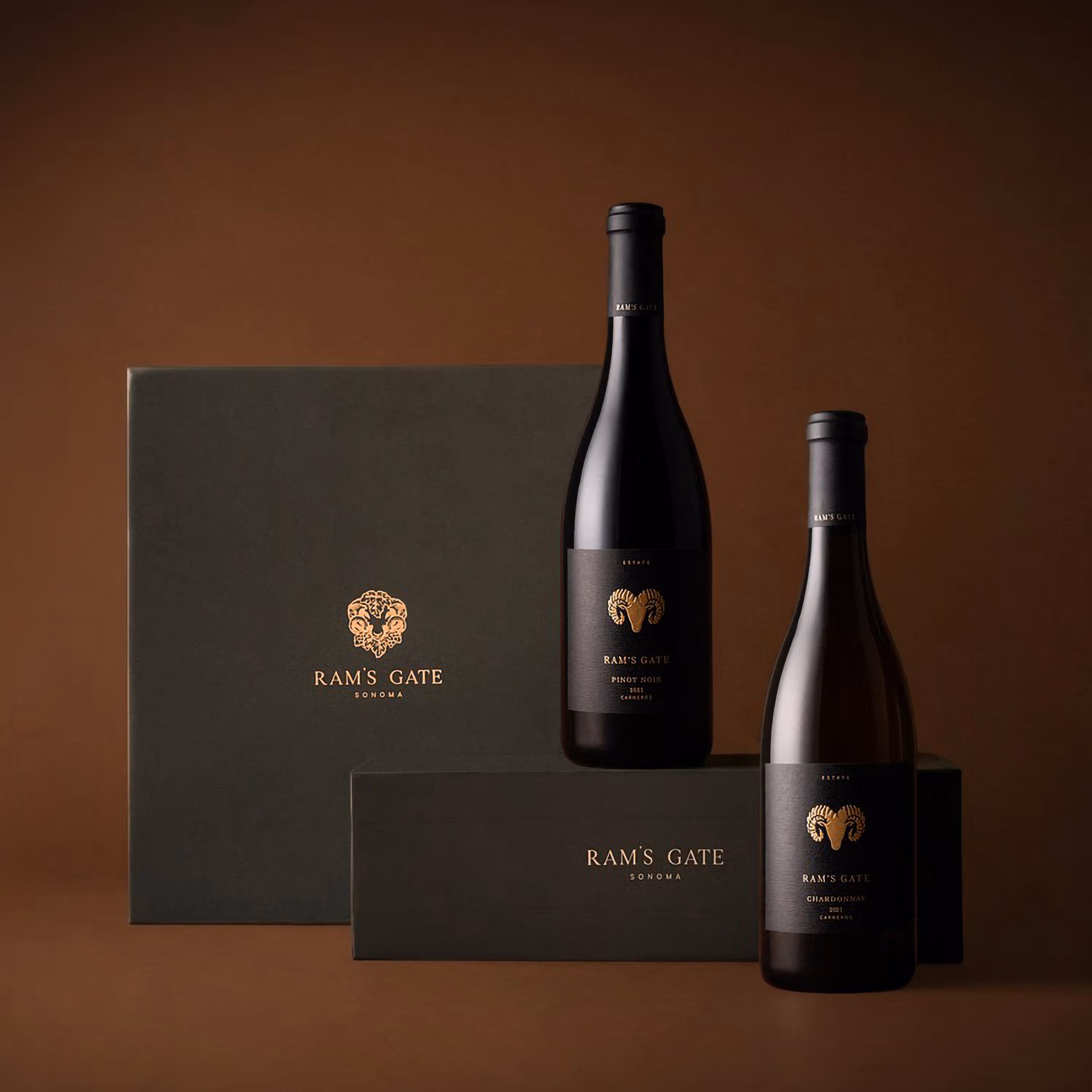 Two premium Ram's Gate wine boxes sitting side by side with two wine bottles in a moody earthy tone background.