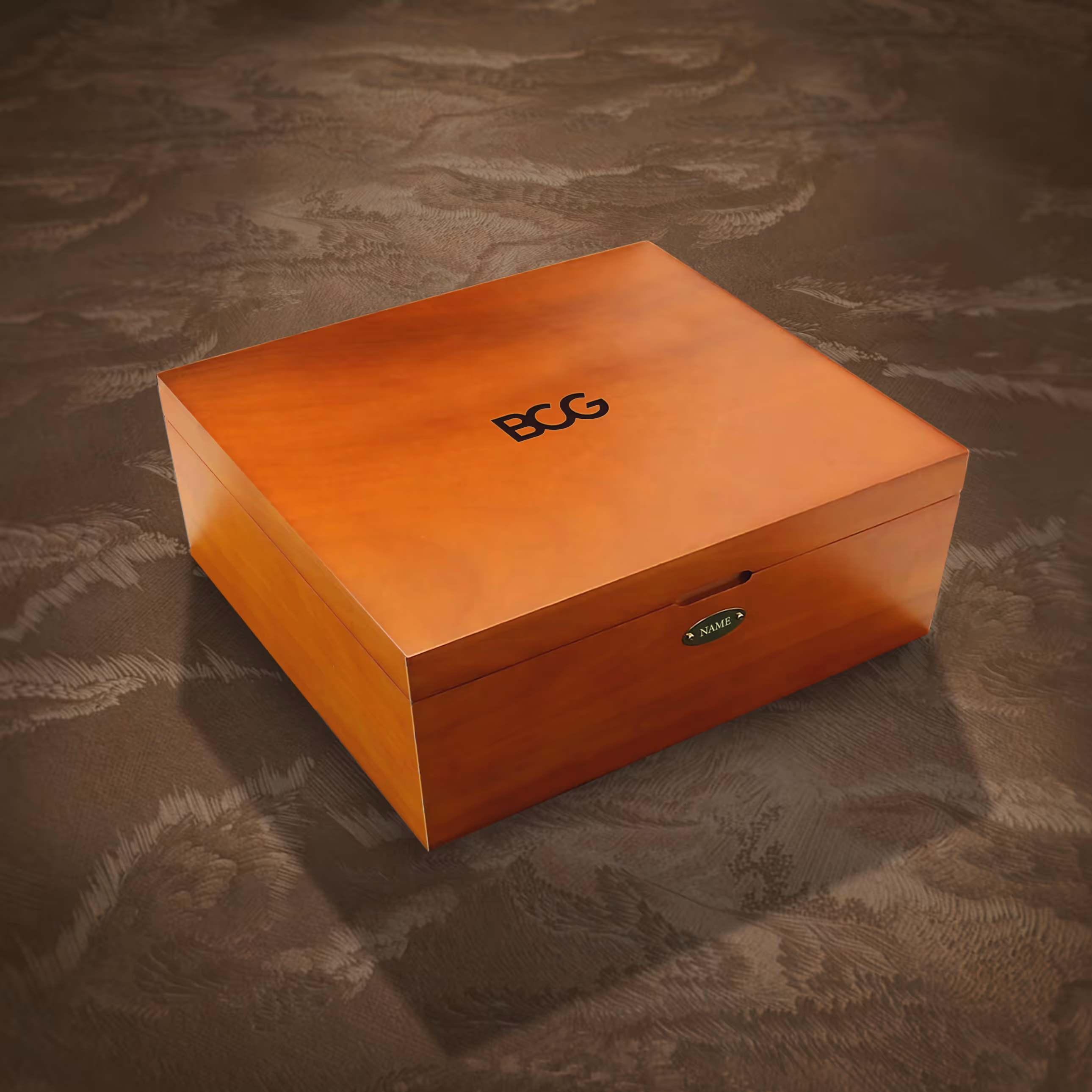 A wood veneered closed BCG wooden box with gold name plaque in an artsy background. 
