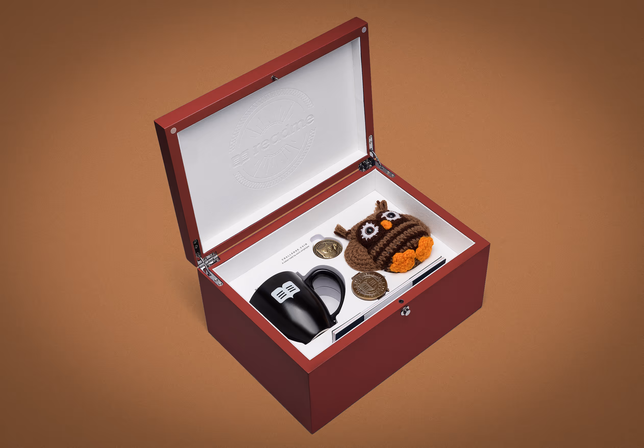 Open wooden Readme new hire box with the brand's plushie, cup, compass and coin.