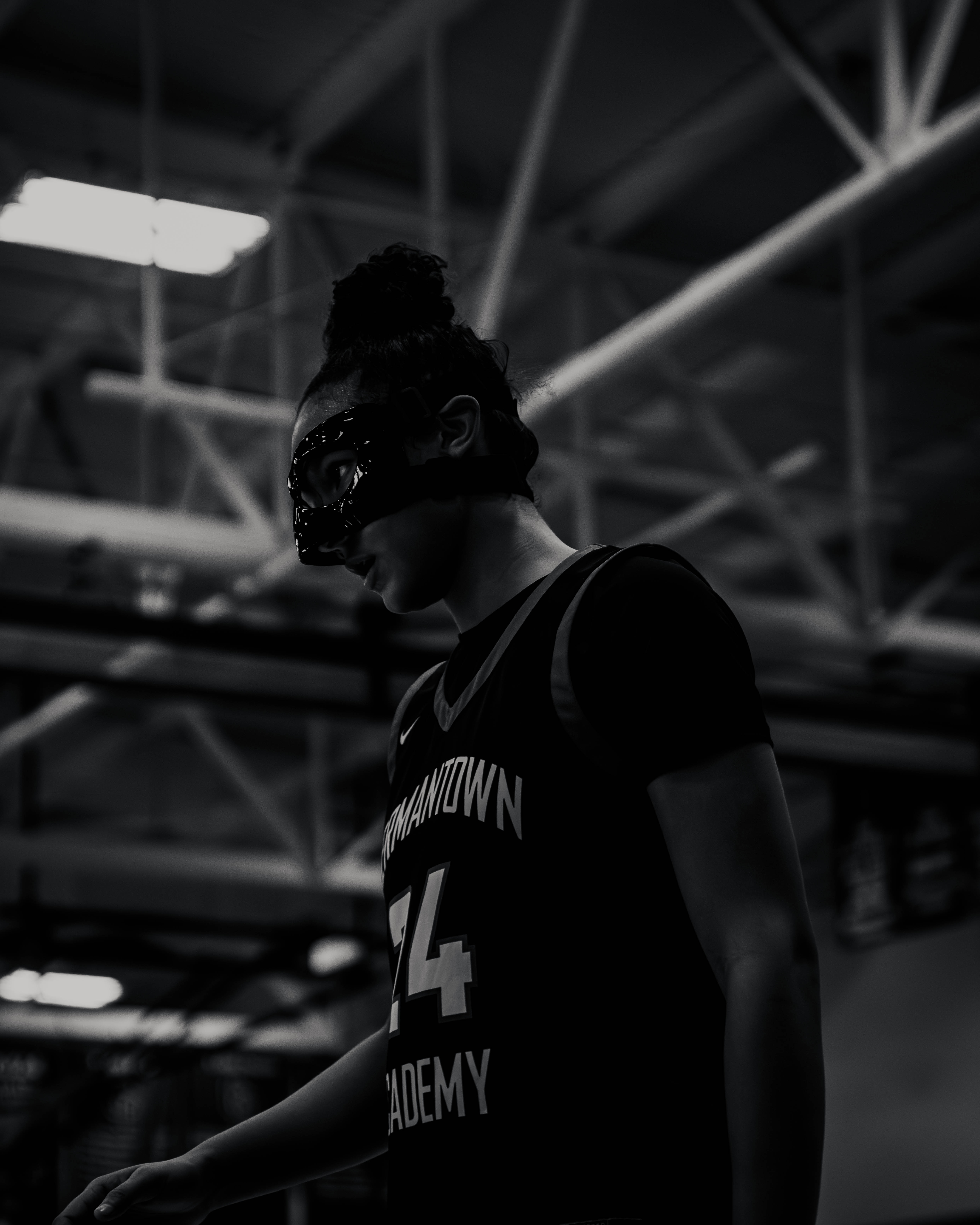 Basketball player wearing a protective face mask and a numbered jersey in a gymnasium.