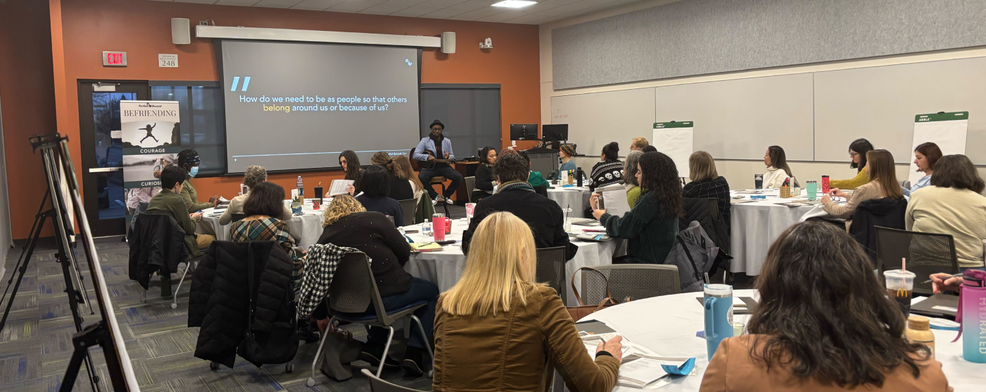A room full of people listening to Parfait speak during the befriending summit