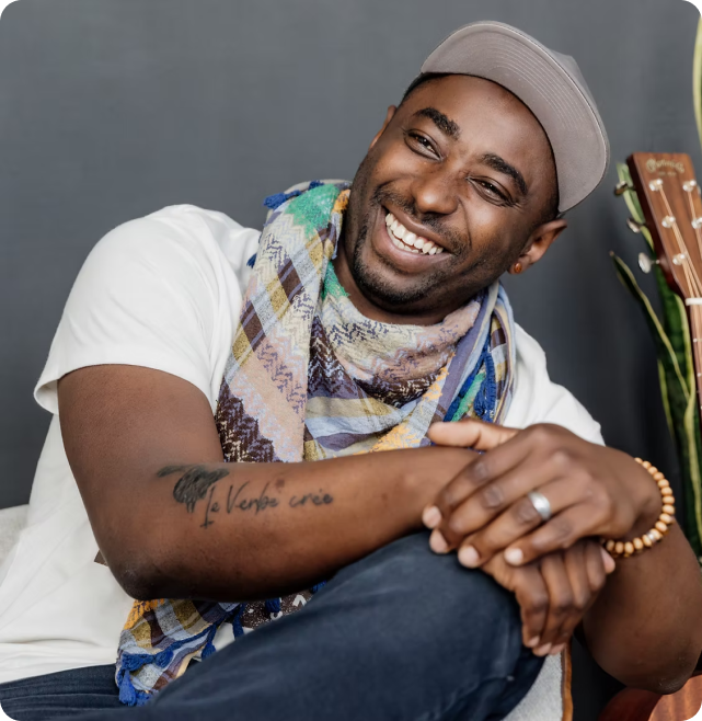 Parfait Bassalé sitting with his hands on his knees and smiling