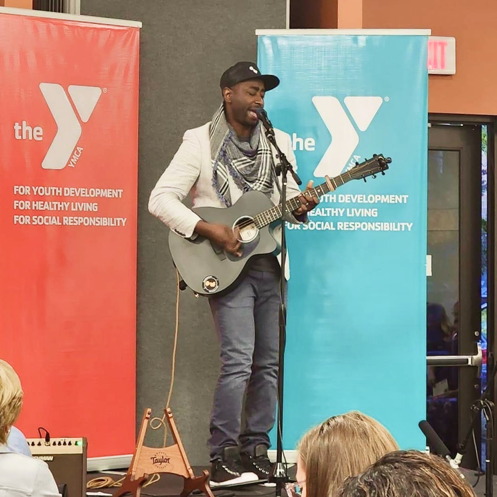 Parfait performing music with his guitar to a crowd