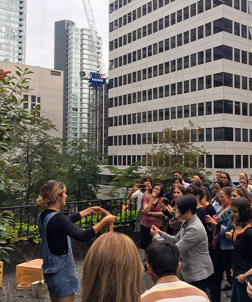 Alvéole beekeeper shows a frame of honey bees to a group of people during a workshop