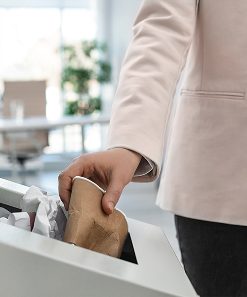 A person places a paper cup in the recycling. design de bureau durable