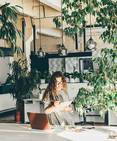 An employee working in an office filled with indoor plants
