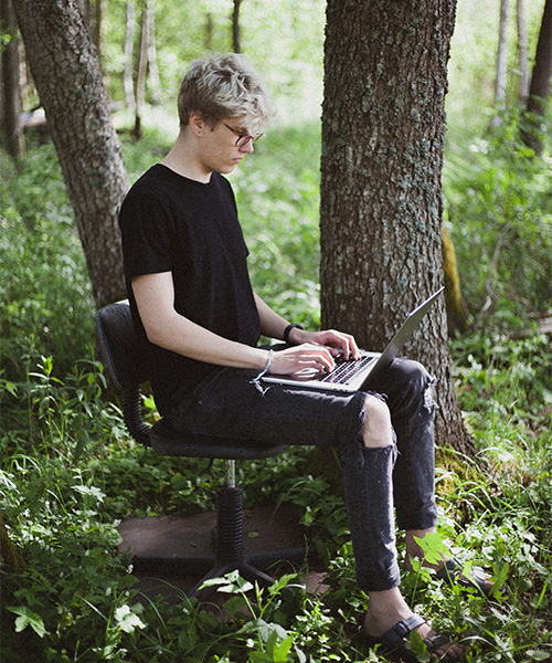 Une personne est assise sur une chaise de bureau et tape sur un ordinateur portable.