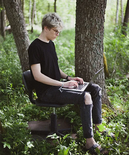 Une personne est assise sur une chaise de bureau et tape sur un ordinateur portable.