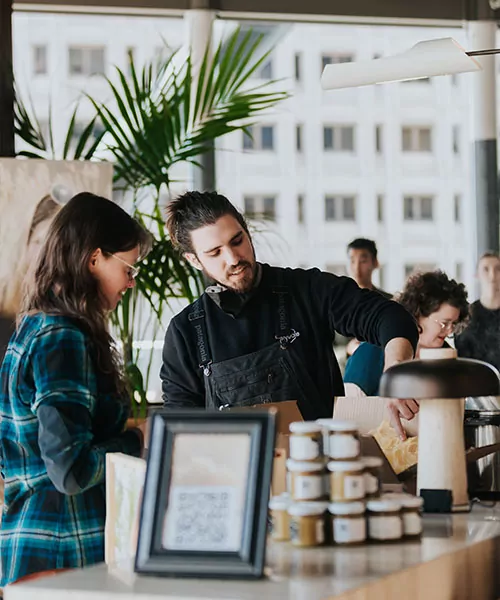 Un apiculteur s'entretient avec une femme devant un étalage de pots de miel. certification de bâtiment vert