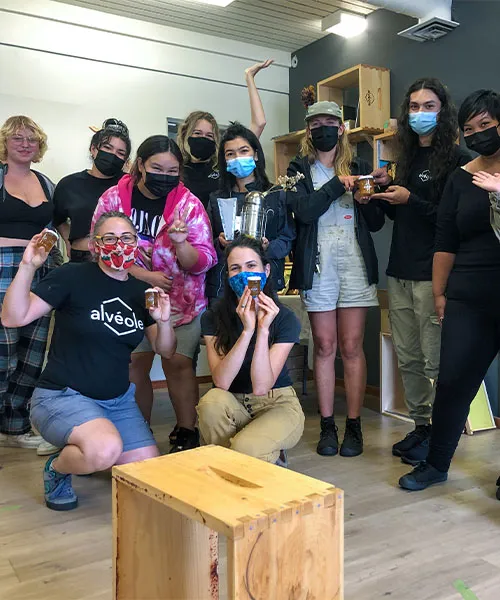 Hive to Honey Jar workshop with Environmental Youth Alliance. A group of Alvéole team members and EYA volunteers smile holding jars of honey. sustainable youth programs