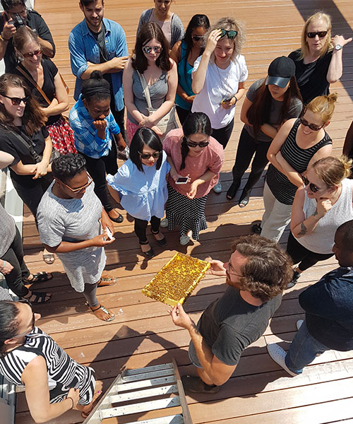 Un apiculteur d'Alvéole montre un cadre d'abeilles à des clients sur un toit.