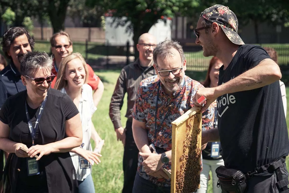 An urban beekeeper holding a honeycomb frame to a group of adult during an Alvéole workshop.increase property value
