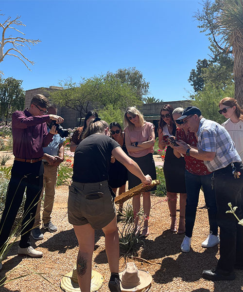Une apicultrice montre un cadre remplie d'abeilles à un groupe de personnes lors d'un atelier. augmenter la valeur de votre propriété