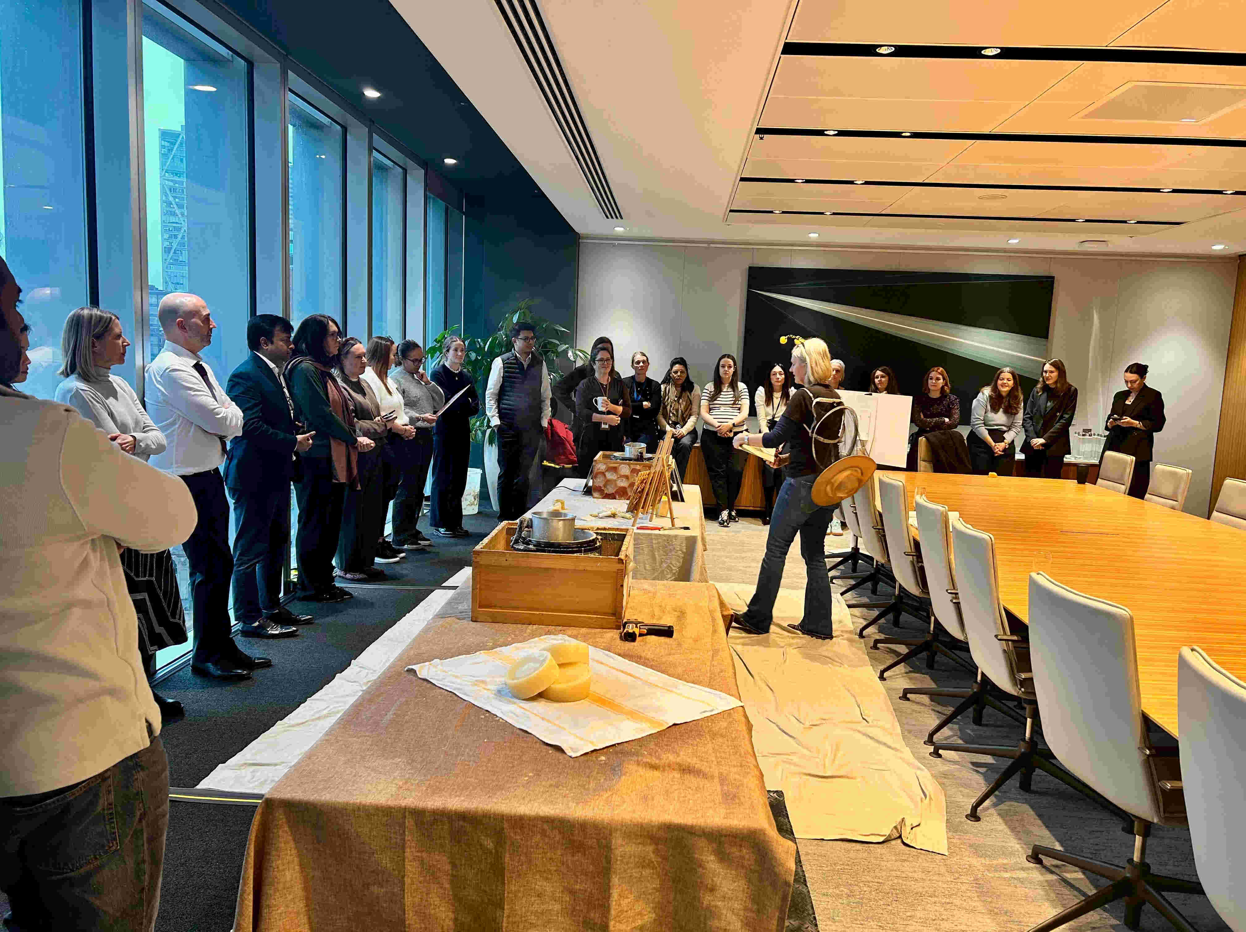 Employés de RBC Marchés des Capitaux réunis autour d'une apicultrice Alvéole lors d'un atelier de récolte de miel dans une salle de conférence à Londres