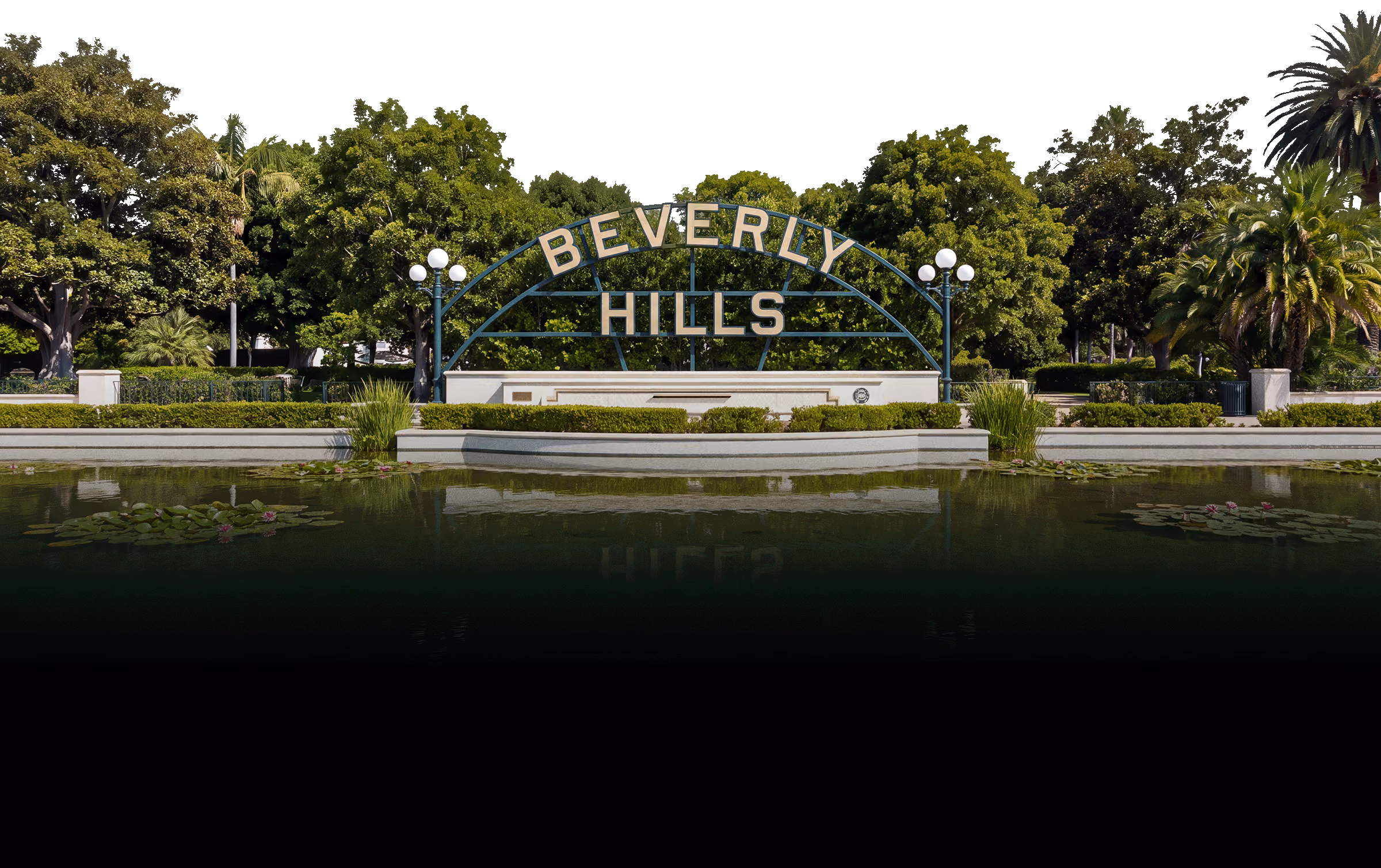 Beverly Hills sign in front of lush green trees with lamp posts and a reflecting pond.