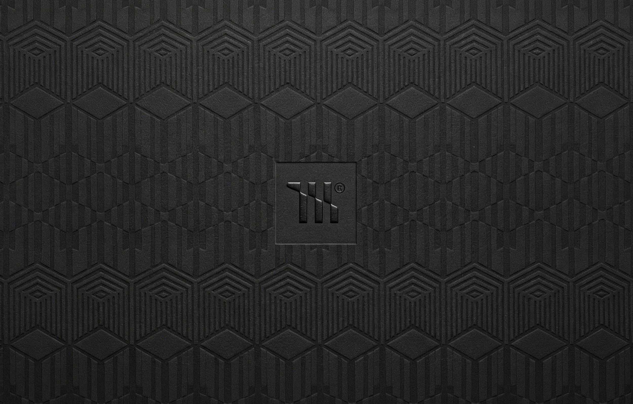 Mariachi Gold Coast Creative Studio Brand image. Black textured surface with geometric patterns and an embossed square logo in the center featuring capital letters 'TK'.