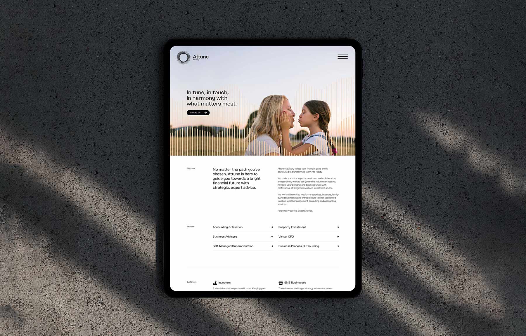 Attune Advisory Brand image. Tablet displaying Attune Advisory website homepage with a banner image of a woman and young girl touching faces and company services and descriptions below.
