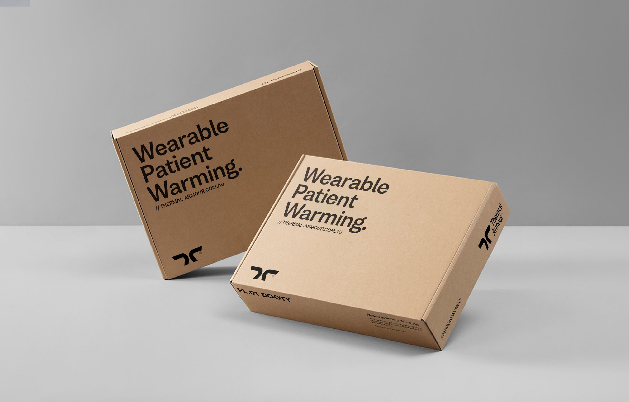 Thermal Armour Packaging. Two brown cardboard boxes with text 'Wearable Patient Warming' and the Thermal Armour logo on a grey surface.