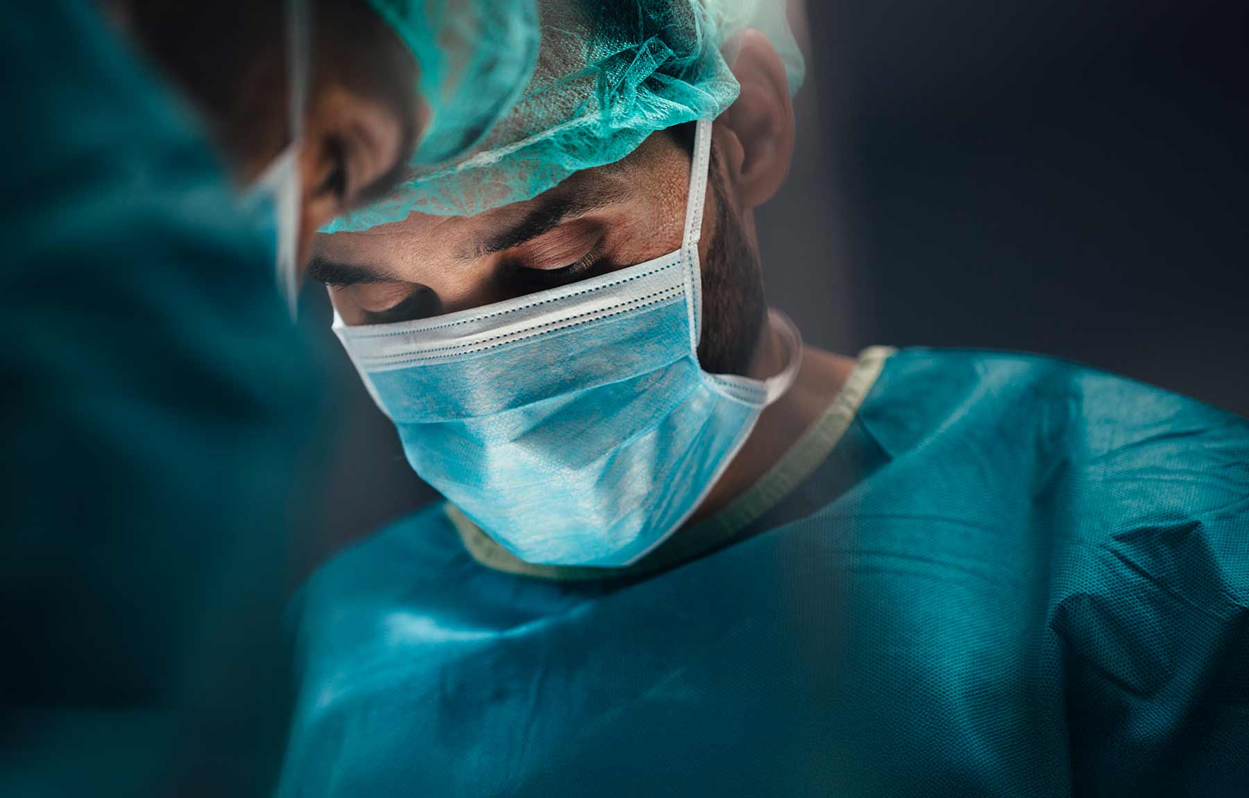 Panacea Ai brand Image. Two surgeons wearing surgical masks and green scrubs focused during an operation.
