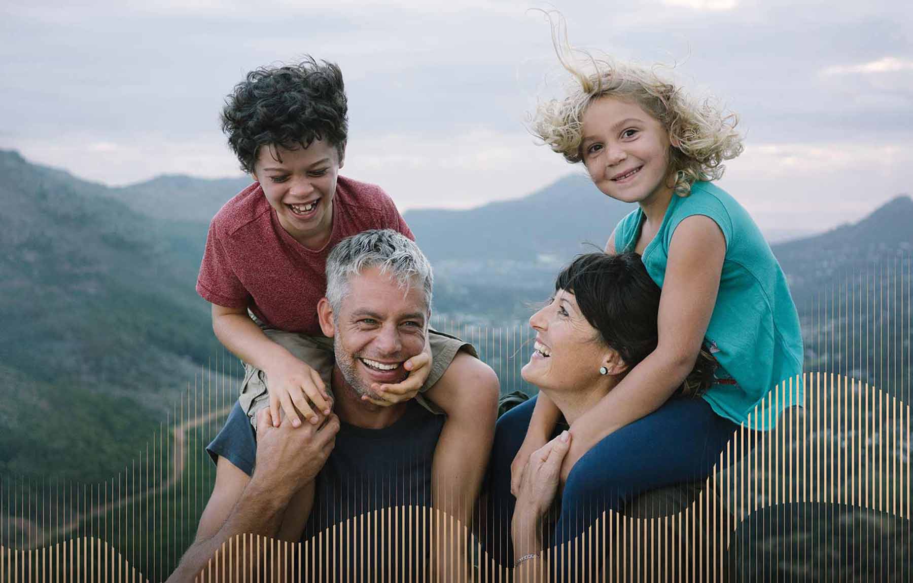 Attune Advisory Image. Smiling parents carrying their laughing children on their shoulders with mountains in the background.