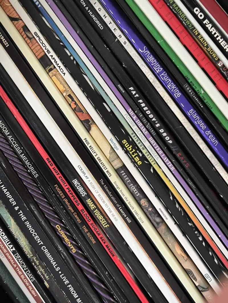 Stack of various music vinyl records with visible artist names and album titles including Red Hot Chili Peppers, Paul Kelly, Sublime, Incubus, and Fleet Foxes.