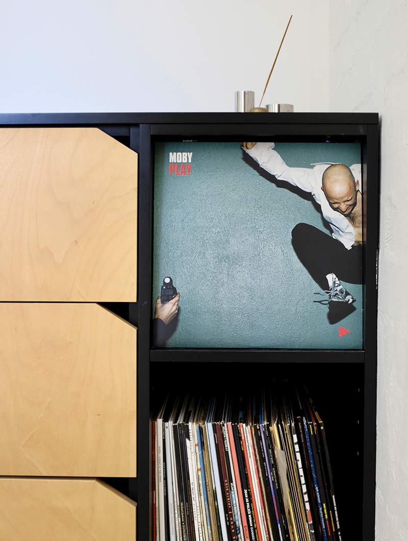 Vinyl record album 'Play' by Moby displayed in a modern black and wood storage unit above a collection of vinyl records.