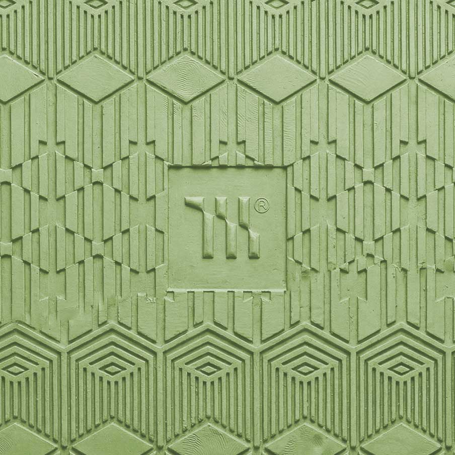 Mariachi Gold Coast Creative Studio brand image. Close-up of a green textured surface with geometric patterns and a central embossed square featuring the letters 'TIK' and a registered trademark symbol.