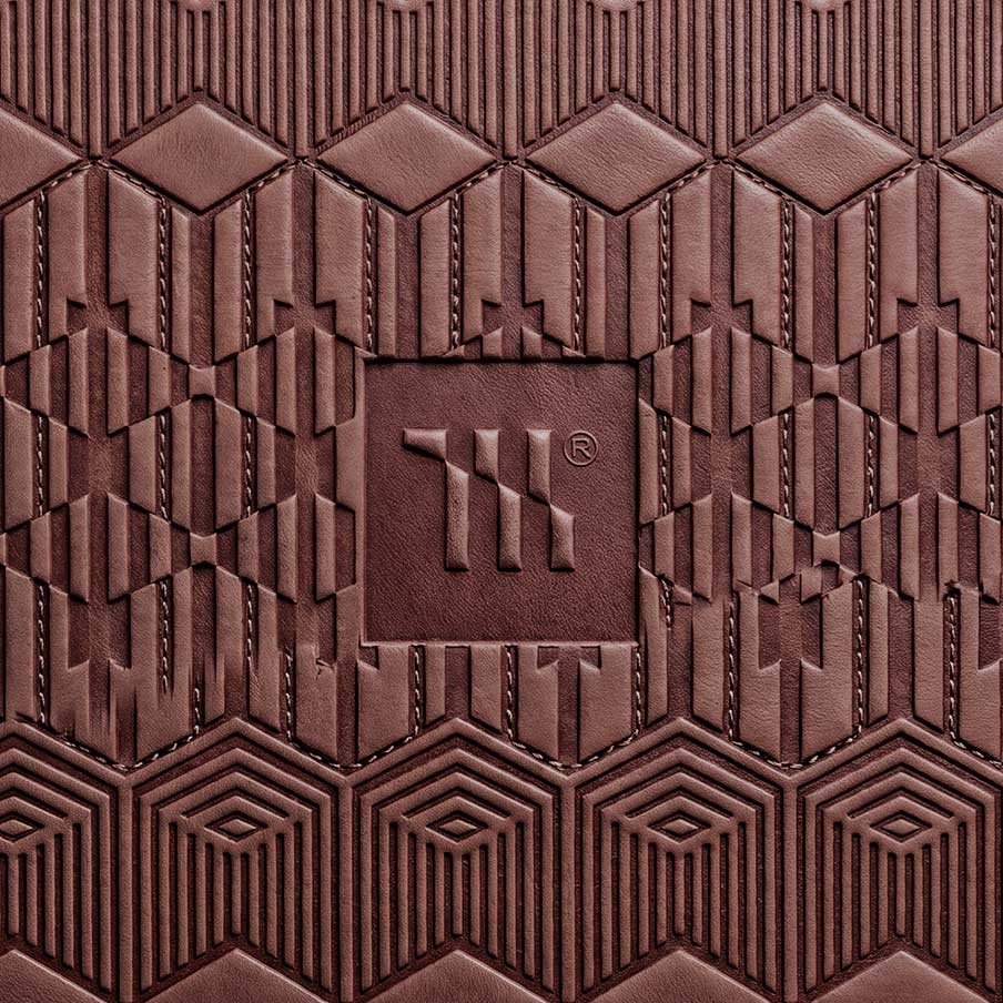 Mariachi Gold Coast Creative Studio Brand image. Close-up of textured brown leather with embossed geometric patterns and a logo in the center.