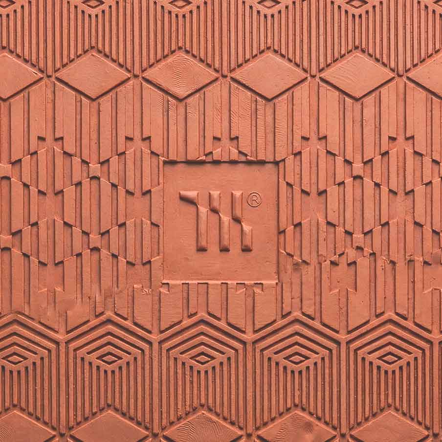 Mariachi Gold Coast Creative Studio Brand image. Textured terracotta surface with geometric patterns and an embossed logo reading 'TIL' with a registered trademark symbol.