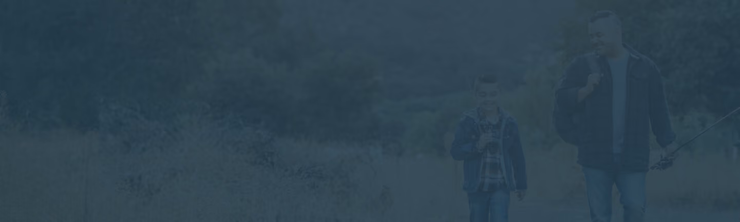 Adult and child walking outdoors together holding fishing rods.