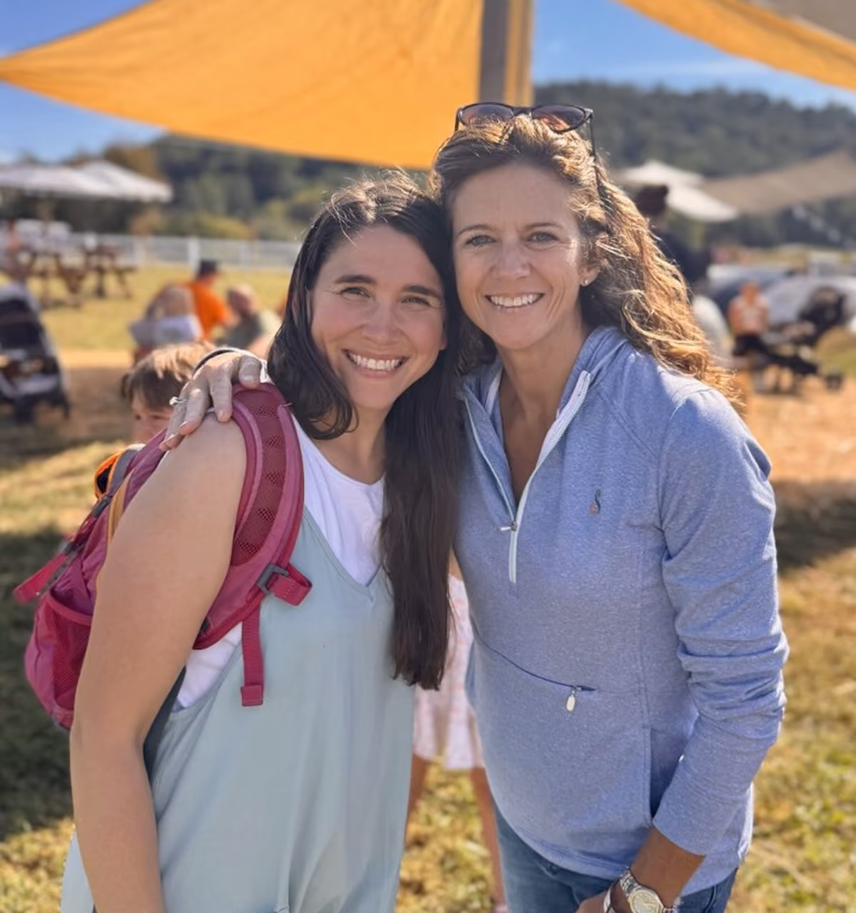 Two smiling women posing outdoors with one woman's arm around the other's shoulder.