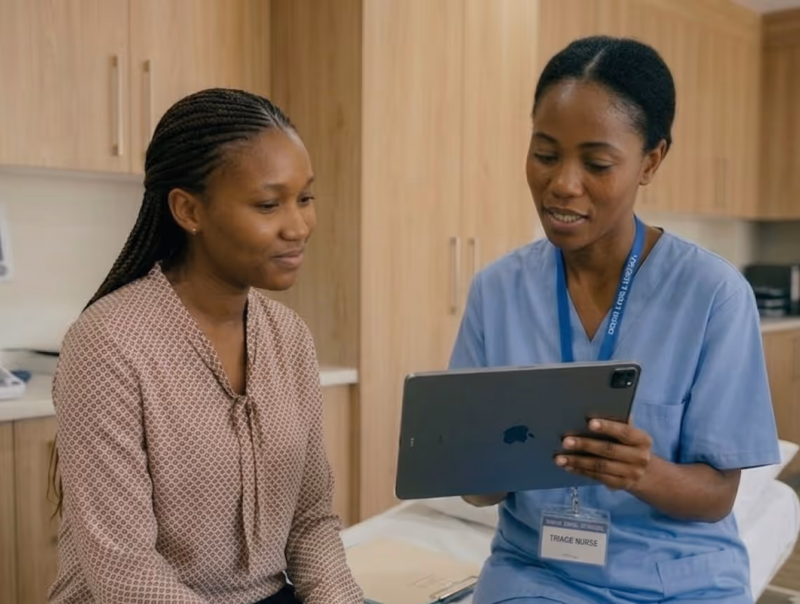 Triage nurse showing information on a tablet to a seated woman in a medical setting.