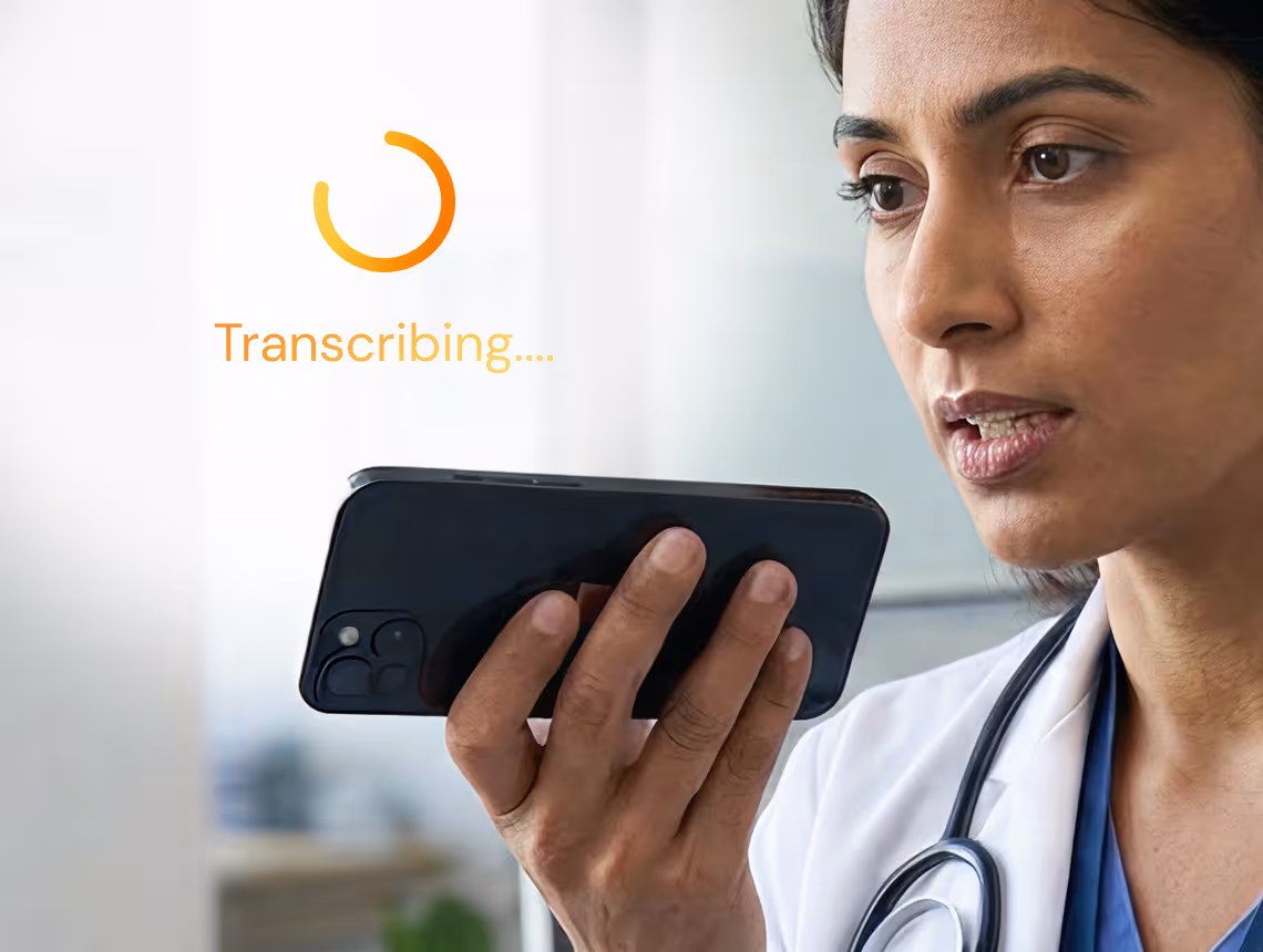 Healthcare worker holding phone and using voice transcription app showing spinning icon and 'Transcribing' text.