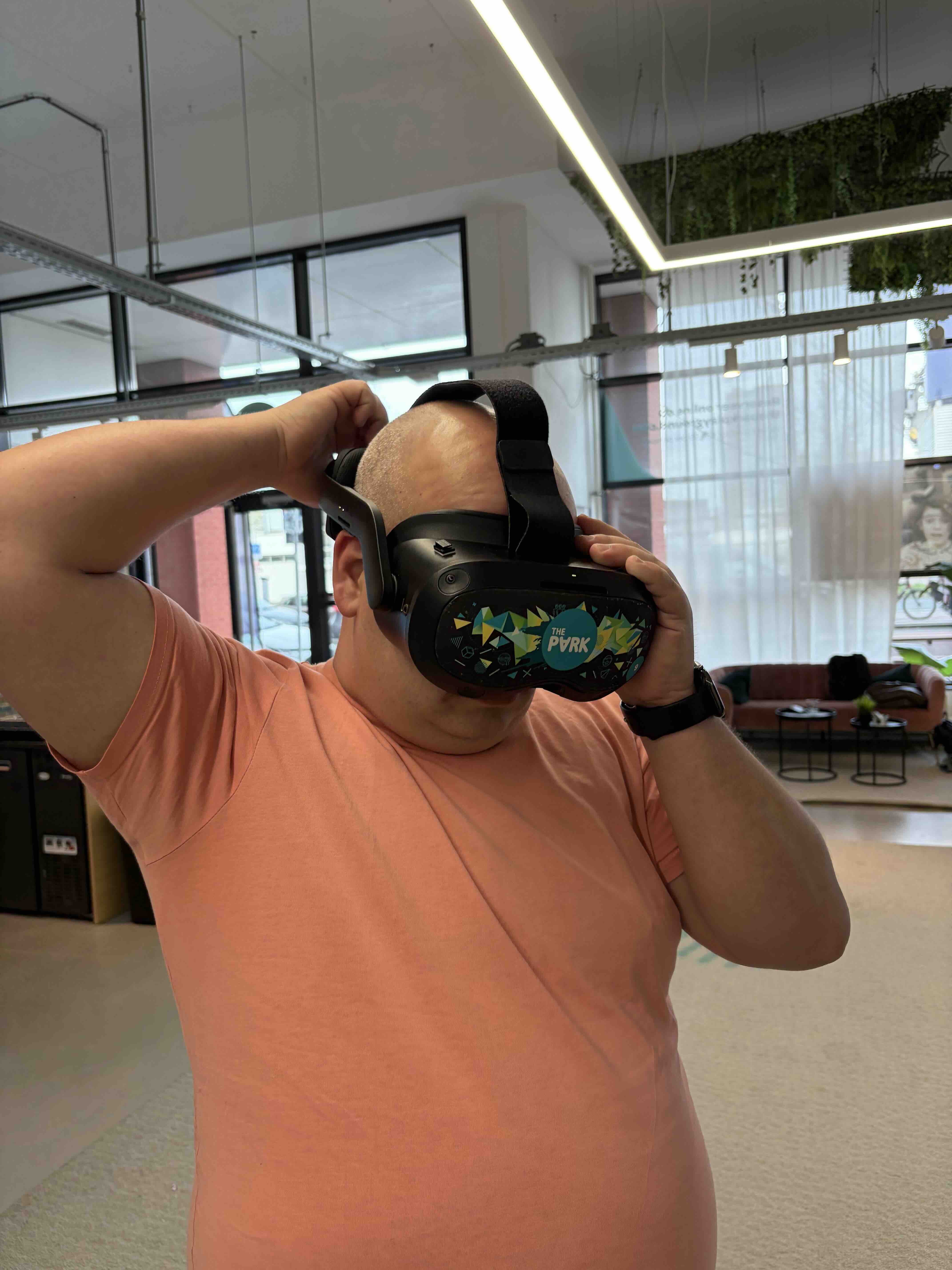 Man die een virtual reality-headset met het label 'The PVRK' opzet in een moderne kantoorruimte.