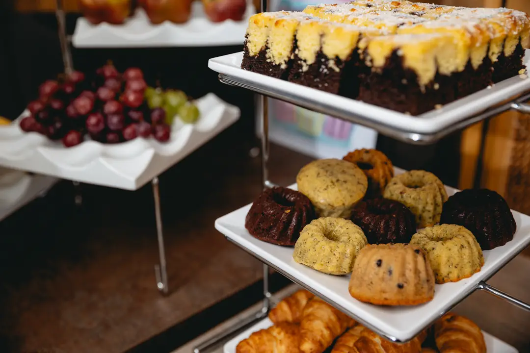 Dreistöckiges Serviergestell mit Schokoladenkuchen, Mini-Gugelhupf, Croissants und Trauben.